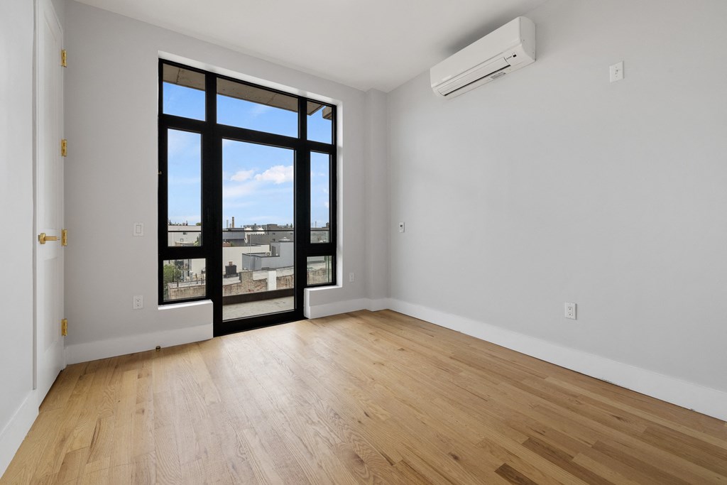 an empty living room with a large window and wooden floors